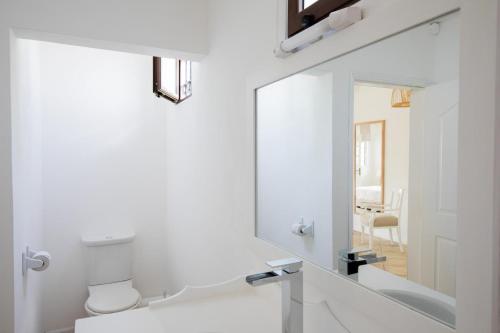 a white bathroom with a mirror and a toilet at Quaint 4BDR villa with pool in Grand Gaube in Grande Gaube