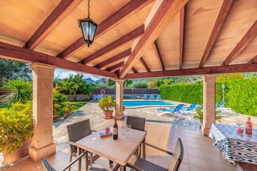a wooden pergola with a table and chairs on a patio at Can Plaseta in Pollença