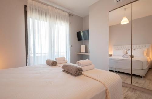 a white bedroom with a bed and a mirror at Bellevue Villas with private pool in Hanioti