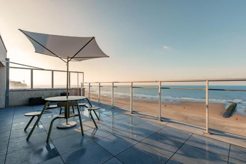una mesa y una silla en un balcón con vistas a la playa en ROOFTOP en Ostende
