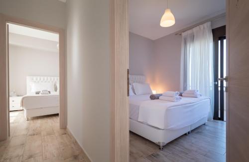 a white bedroom with two beds and a mirror at Bellevue Villas with private pool in Hanioti