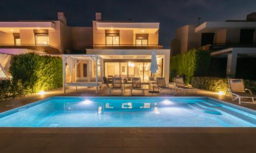 a swimming pool in front of a house at night at Bellevue Villas with private pool in Hanioti