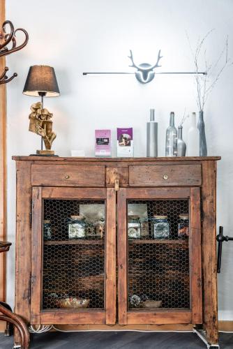 a wooden cabinet with glass doors with a lamp on top at Logis Hôtel et Spa Le Christiania in La Salle Les Alpes