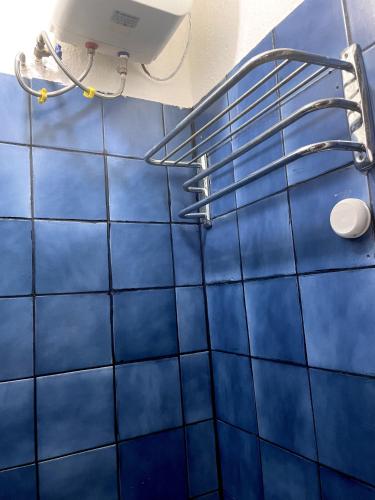 a blue tiled bathroom with a towel rack on the wall at RUDISH COTTAGE (COZY & PRIVATE) in Abuja