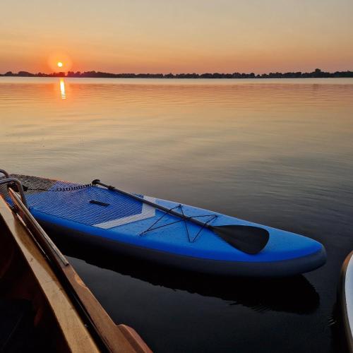 a blue paddle boat sitting on the water at sunset at De WiedenWeide in Wanneperveen