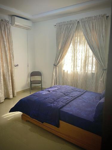 a bedroom with a blue bed and a window at RUDISH COTTAGE (COZY & PRIVATE) in Abuja