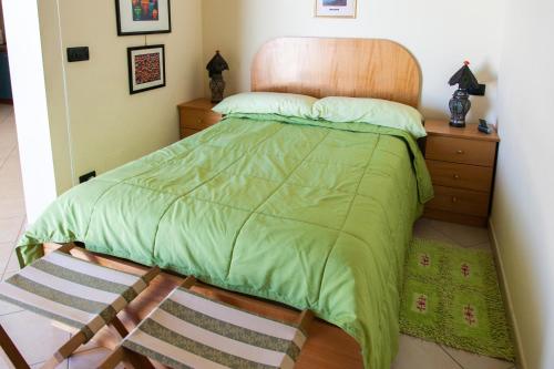 a bed with a green comforter and a wooden headboard at La Terrazza sul Mare in SantʼAgata di Militello