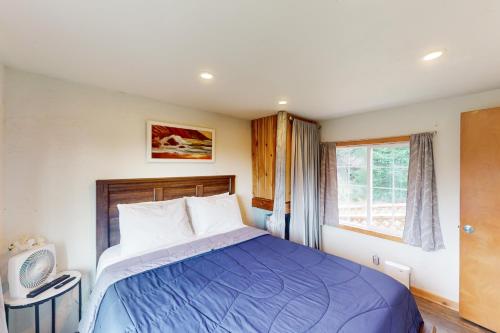 een slaapkamer met een bed met een blauw dekbed en een raam bij Hummingbird Hideout in Port Orford
