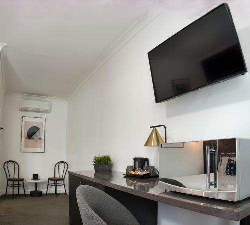 uma sala de estar com uma mesa e uma televisão na parede em Echo Point Discovery Motel em Katoomba