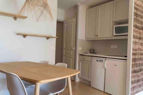 une cuisine avec une table en bois et des armoires blanches dans l'établissement Moment de détente sur le Golf de Pont-Royal, à Mallemort