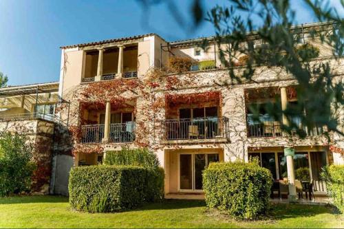 un grand bâtiment avec des buissons devant lui dans l'établissement Moment de détente sur le Golf de Pont-Royal, à Mallemort