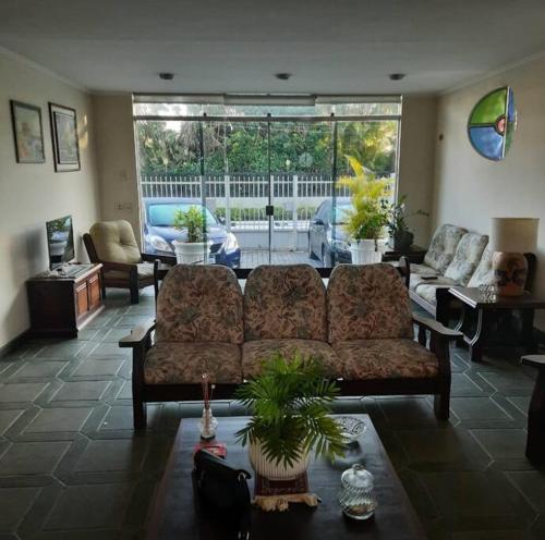 a living room with a couch and a large window at Casa 50m da praia - Enseada/Guarujá in Guarujá