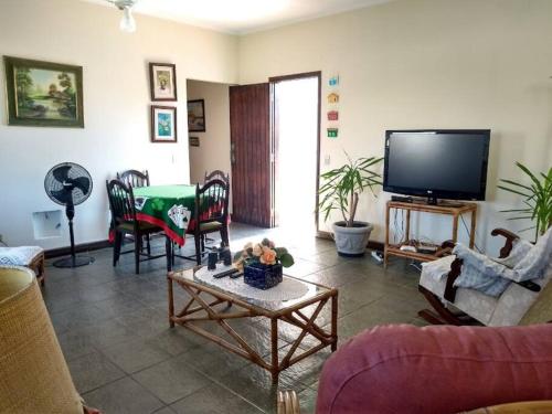 a living room with a tv and a table at Casa 50m da praia - Enseada/Guarujá in Guarujá