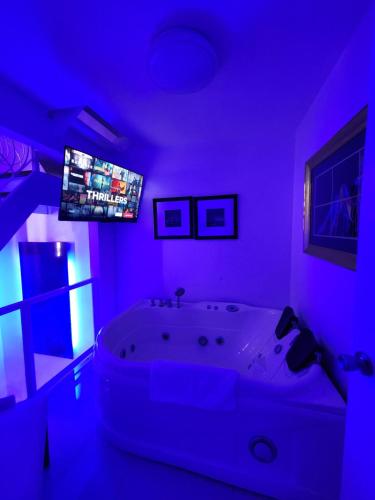 a purple bathroom with a tub and a tv at Kandi Suites 2BR with private Jacuzzi 500 Mbps internet in Angeles