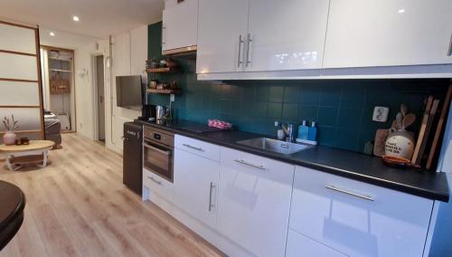 a kitchen with white cabinets and a black counter top at Have a nice stay! - Le Souterrain in Noordwijk aan Zee