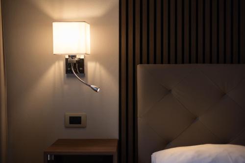 a lamp on a wall next to a bed at Hotel La Fertè in Asti