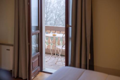 a bedroom with a door open to a balcony with a table at Hotel La Fertè in Asti