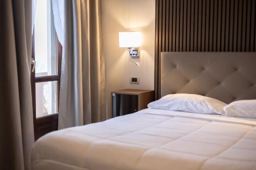 a bedroom with a white bed and a window at Hotel La Fertè in Asti