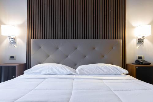 a large white bed with two pillows on it at Hotel La Fertè in Asti