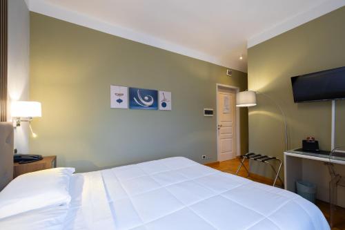 a bedroom with a white bed and a flat screen tv at Hotel La Fertè in Asti