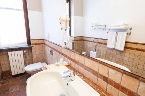 a bathroom with a tub and a toilet and a sink at Hotel La Fertè in Asti