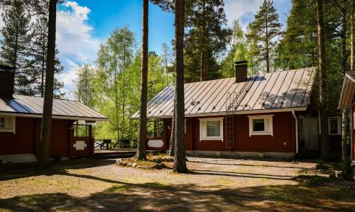 艾赫泰里的住宿－Villa Kuusiranta，一座红色的房子,有金属屋顶和树木