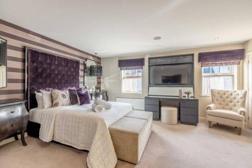 a bedroom with a large bed and a tv at Elegant 4-Bed Home,Private Garden,Parking in Virginia Water