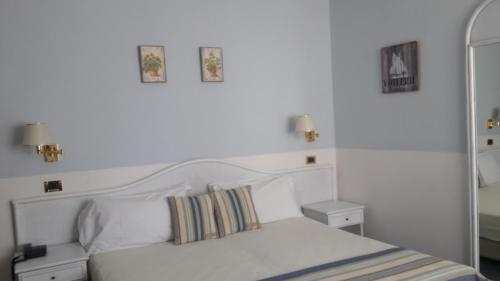 una camera con un letto bianco con due immagini sul muro di Hotel Villa Tiziana a Lido di Venezia