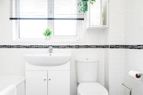 La salle de bains blanche est pourvue de toilettes et d'une fenêtre. dans l'établissement Cosy 3 Bedroom House with Free Parking and Garden, à Earley