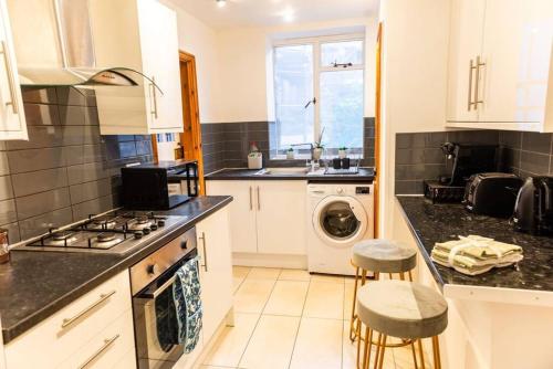 a kitchen with a stove top oven next to a washing machine at 3-Bed Apartment Central London - 15 Mins walk to Kings Cross by Seren Short Stays in London