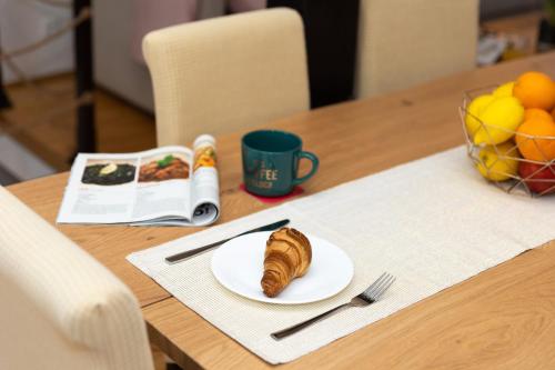 a plate with a croissant on a table with a book at Apartment Centar in Dubrovnik