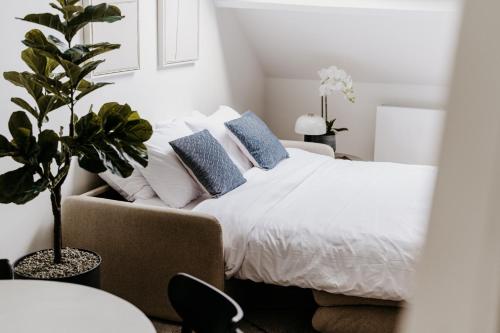 a bedroom with a white bed with blue pillows at Cathedral view from the bathtub in Antwerp