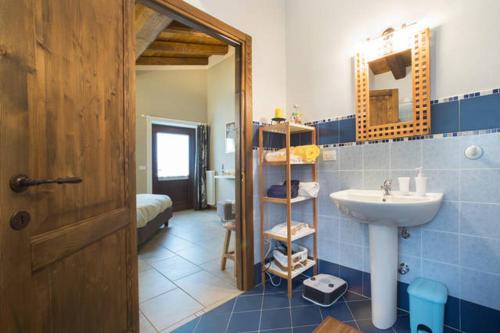 uma casa de banho azul e branca com um lavatório e um espelho em B&B Alla Borgata em Boves