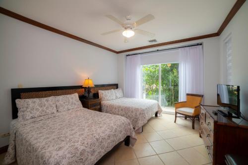 1 dormitorio con 2 camas, TV y ventana en Los Suenos Resort Bay Residence 8C, en Herradura