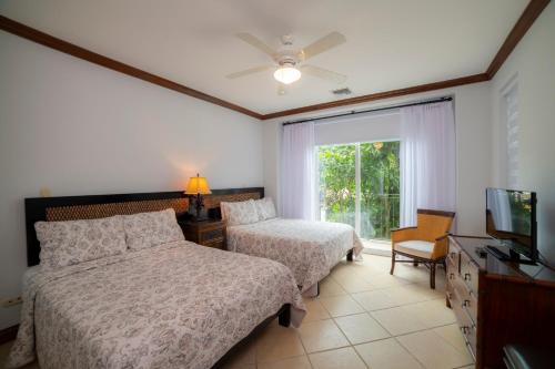 a bedroom with two beds and a tv and a window at Los Suenos Resort Bay Residence 8C in Herradura