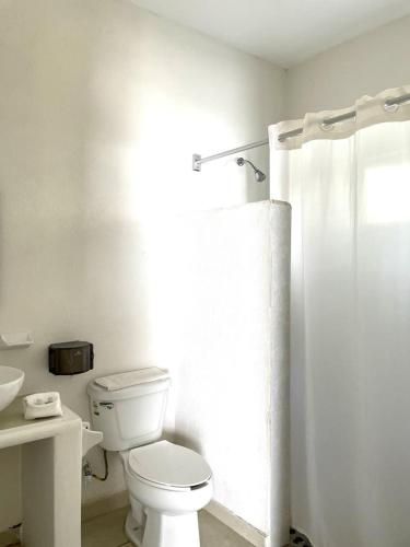 a white bathroom with a toilet and a shower at Bungalows Las Hamacas in San Patricio Melaque