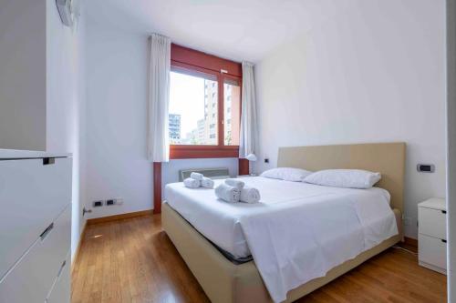 a bedroom with a large white bed with towels on it at Bellissimo bilocale con terrazzo in Milan