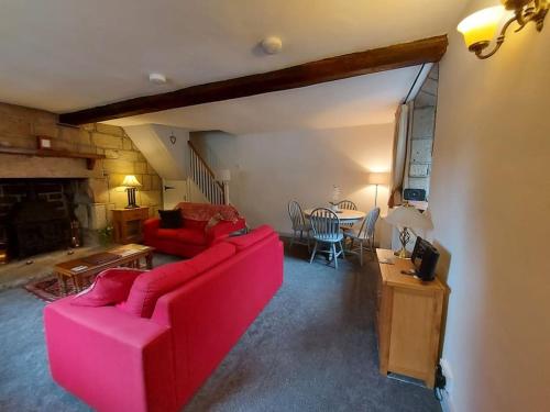 a living room with a red couch and a table at Old Town Hall Holiday Cottage in Hebden Bridge