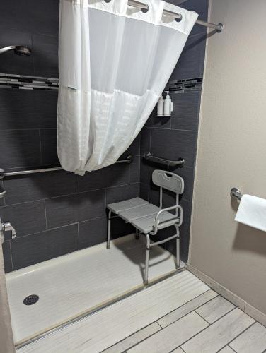 a shower with a chair and a shower curtain in a bathroom at Travelodge by Wyndham Pueblo in Pueblo