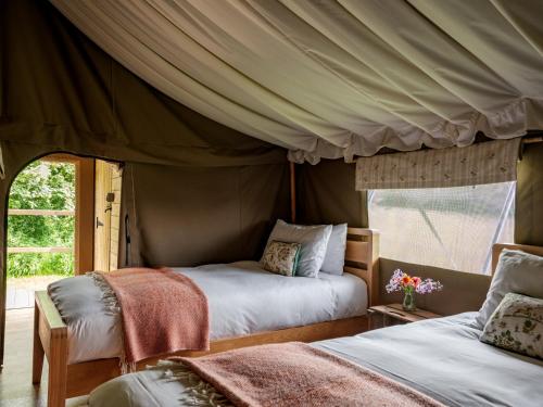 a bedroom with two beds in a tent at Black Pig Retreats Luxury Glamping in Shaftesbury