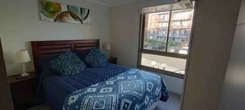- une chambre avec un lit doté d'une couette bleue et d'une fenêtre dans l'établissement Departamento Cumbres de Miramar, à San Antonio