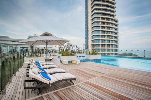 una terraza con sillas, una sombrilla y una piscina en Pearls of Umhlanga Apts, en Durban