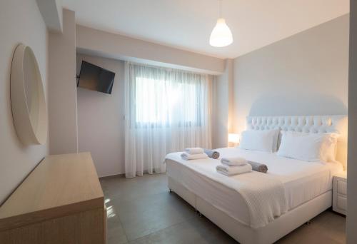 a bedroom with a white bed with towels on it at Bellevue Villas with private pool in Hanioti