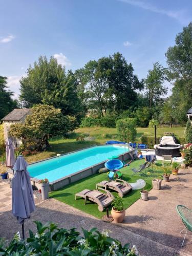 a swimming pool with chaises and chairs in a yard at Chambres d'Hôtes de l'Ile du Saule in Saumur