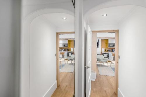 a hallway with white walls and a room with chairs at City Ground Floor Flat on St Stephens Rd in Norwich