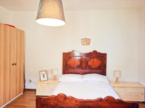 een slaapkamer met een groot bed met een houten hoofdeinde bij 2 bedrooms apartement with city view balcony and wifi at Carisolo in Carisolo