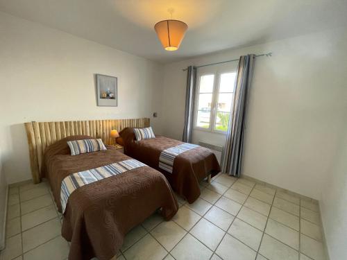 a bedroom with two beds and a window at Paradiles in Dolus-d'Oléron