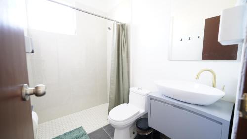 a white bathroom with a sink and a toilet at Caribbean Stars San Juan Airport in Carolina