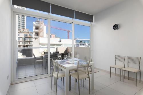 a dining room with a table and chairs and a large window at Spacious & Stylish 3BR Penthouse With Large Terrace - Close to Spinola Bay in St Julian's