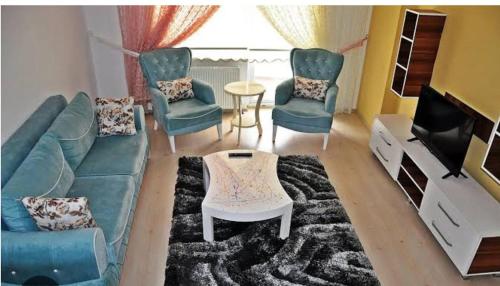 een woonkamer met een bank en stoelen en een tv bij Rojda Apartman in Istanbul